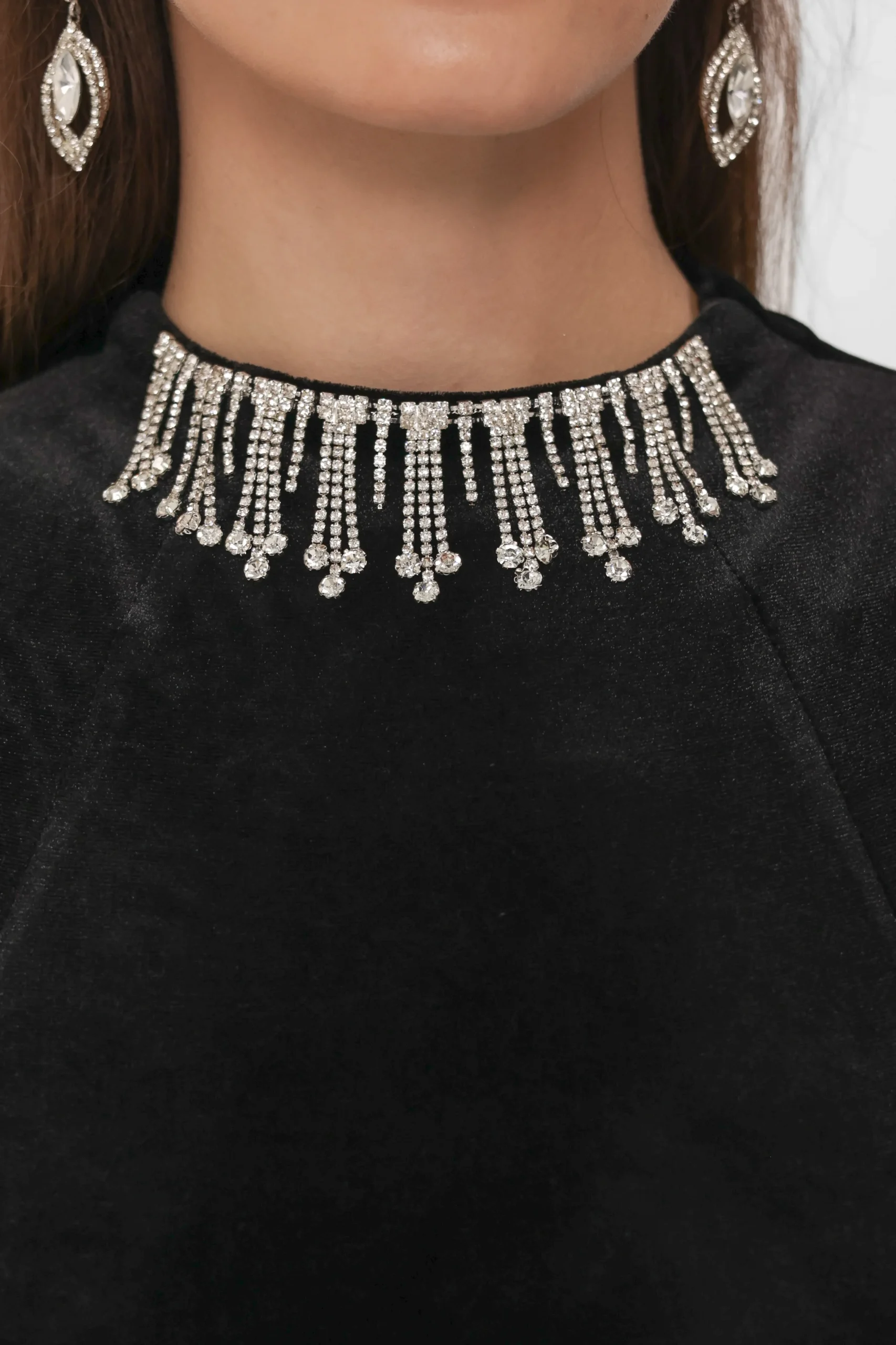 Crystal fringe necklace at the neckline of the velvet jumpsuit