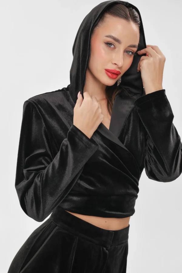 Model pulling up the hood of the black velvet wrap top by REPULO’S