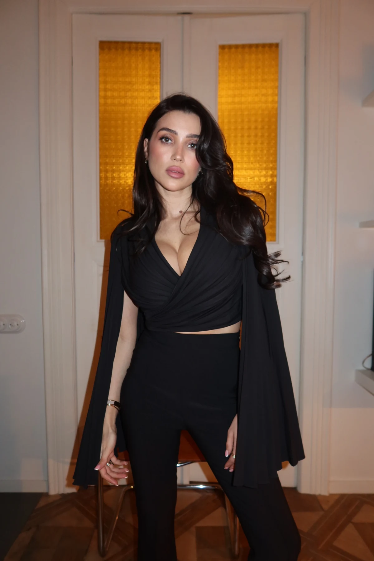 REPULO'S model in the black Dream crop wrap blouse with pleated sleeves, an example of clothing fit after breast augmentation