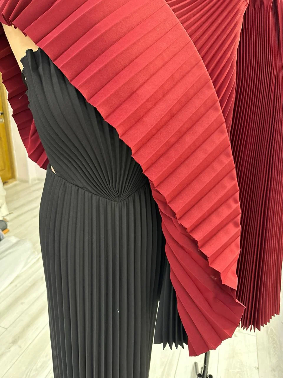 Black pleats with a fan bodice and voluminous ripe cherry pleats on a mannequin