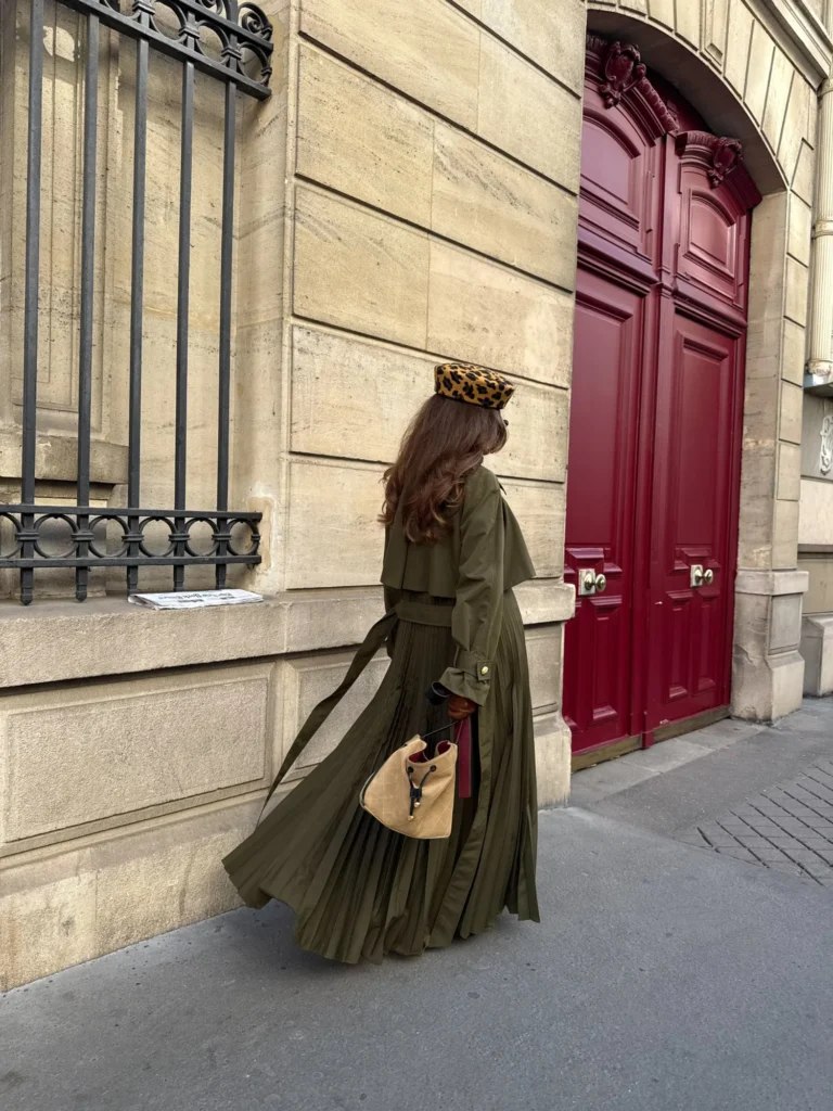 The pleated back of the Amber trench coat opening as she walks