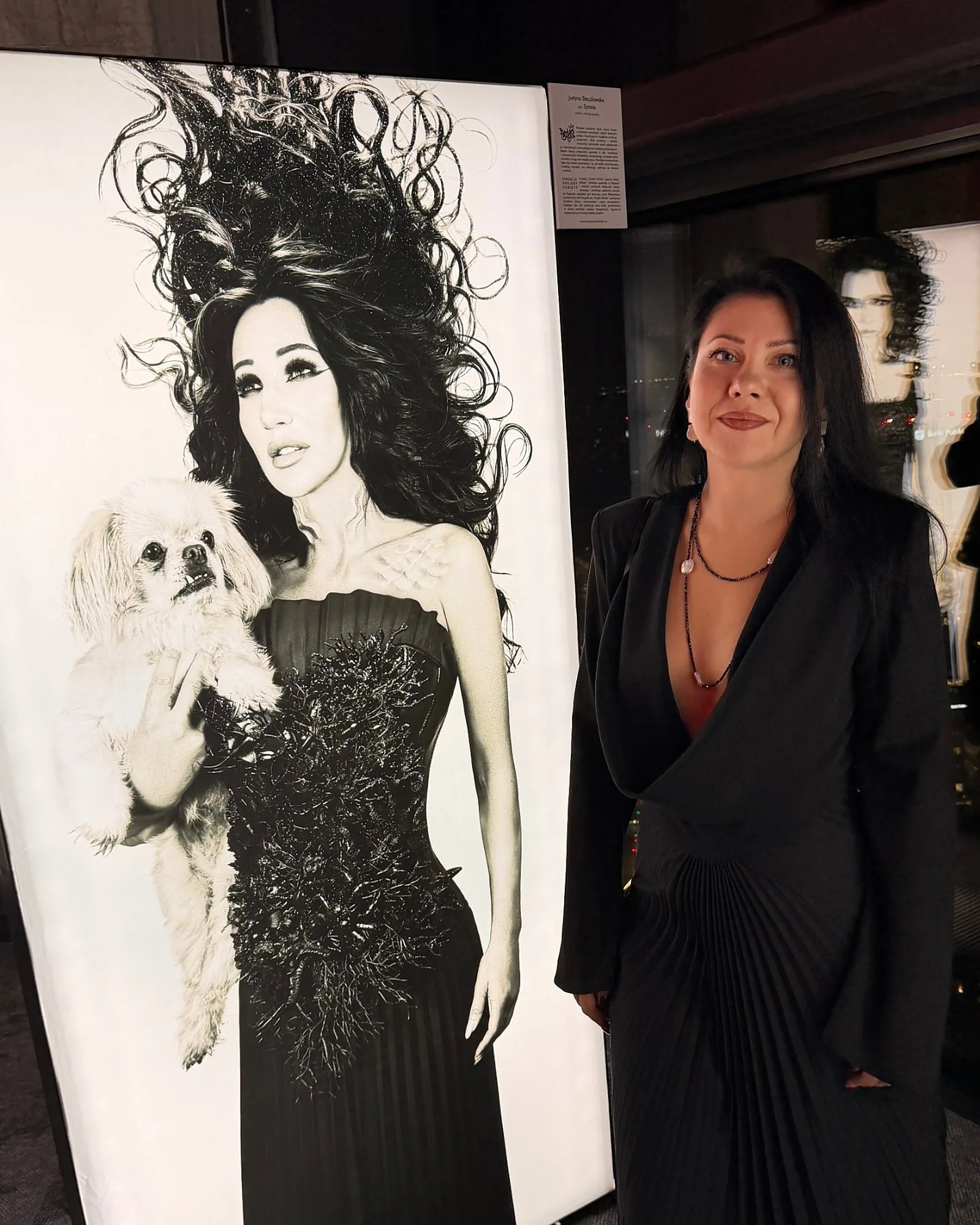 REPULO'S designer Kateryna Nechyporenko in the pleated Halo gown next to Justyna Steczkowska's Siren portrait at the Bad Girls exhibition in Varso Tower, Warsaw